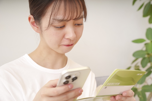 通帳を見て厳しい顔を浮かべる女性